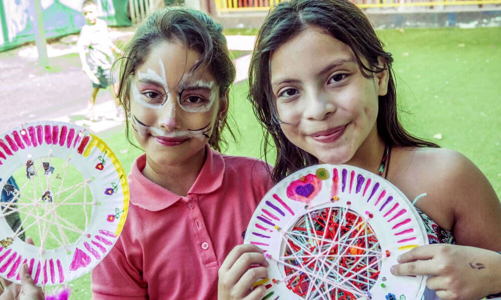Kinder lächeln mit Gebasteltem in die Kamera in Costa Rica