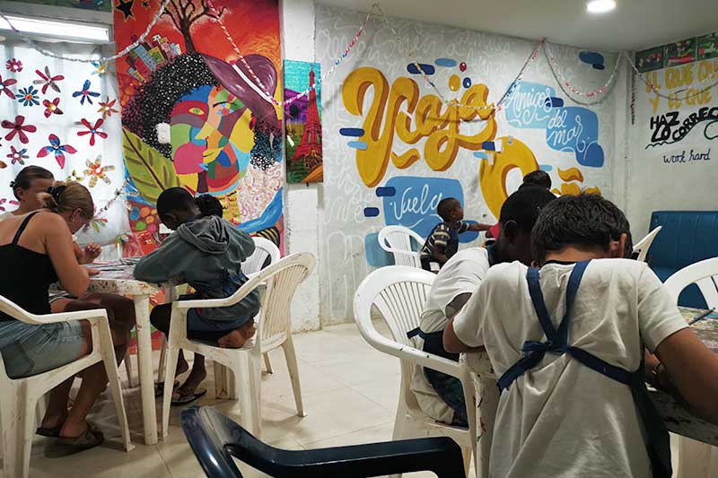 Colombian children sitting on chairs in front of graffiti wall