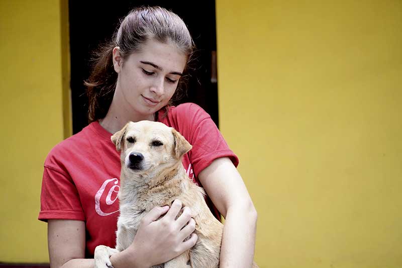 Freiwillige kuschelt mit Hund in der Horse Ranch in Peru