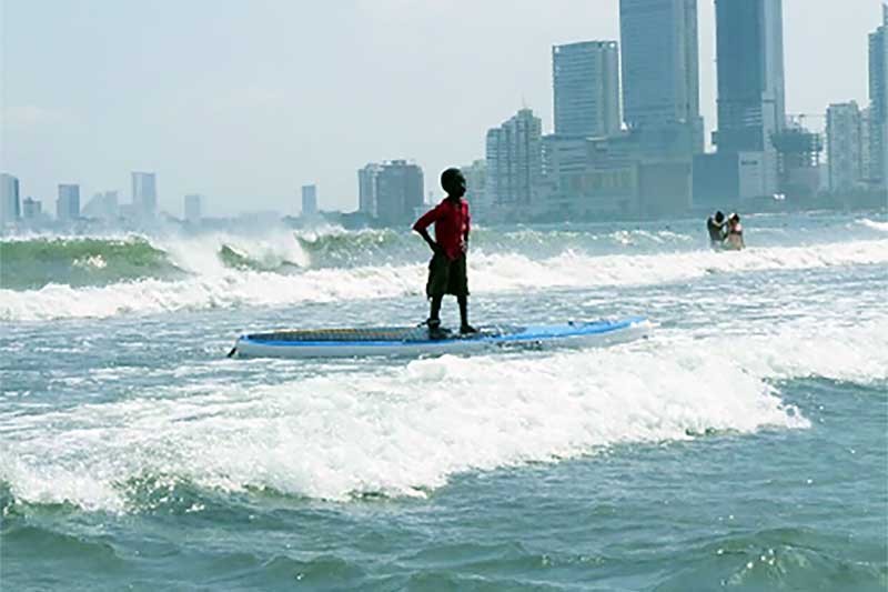 Colombian boy surfing a wave in front of skyline
