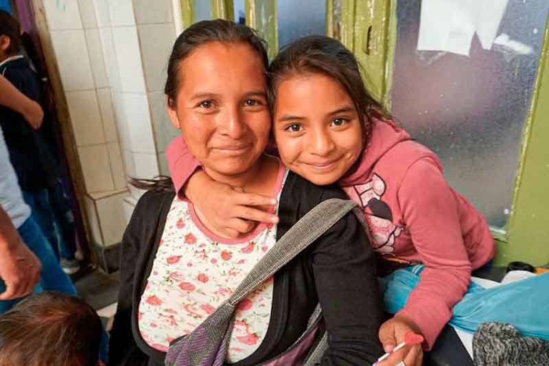 Kind lächelt mit Lehrerin in die Kamera in Mexiko