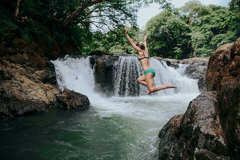 Frau springt in Quellwasser an einem Wasserfall in Costa Rica