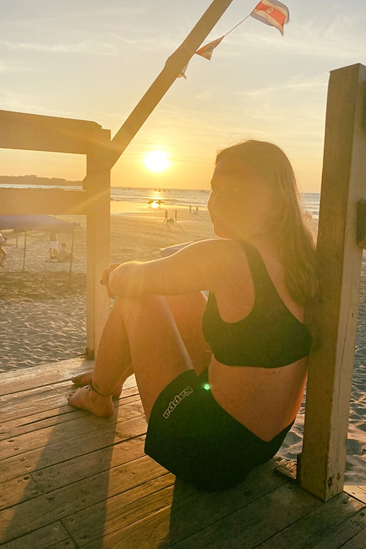 Lena sitzt bei Sonnenuntergang am Strand