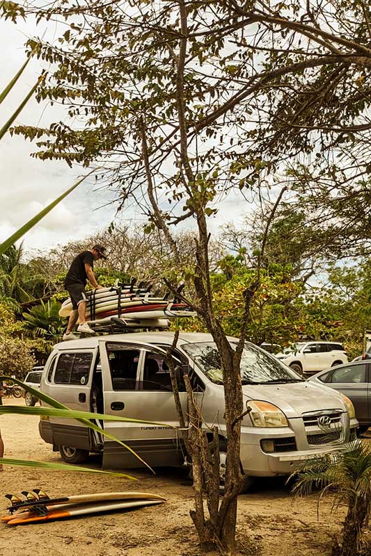 Mann befestigt Surfbretter auf einem Autodach
