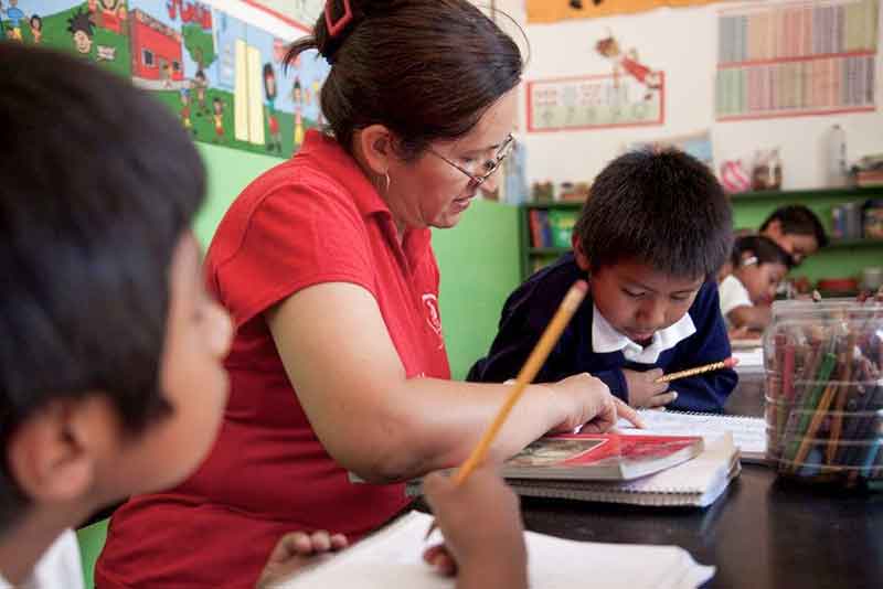 Lehrerin erklärt Kind etwas im Übungsheft in Mexiko