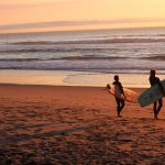 Zwei Surfer am Strand bei Sonnenuntergang