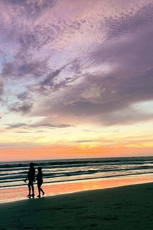 zwei Personen laufen Hand in Hand bei Sonnenuntergang