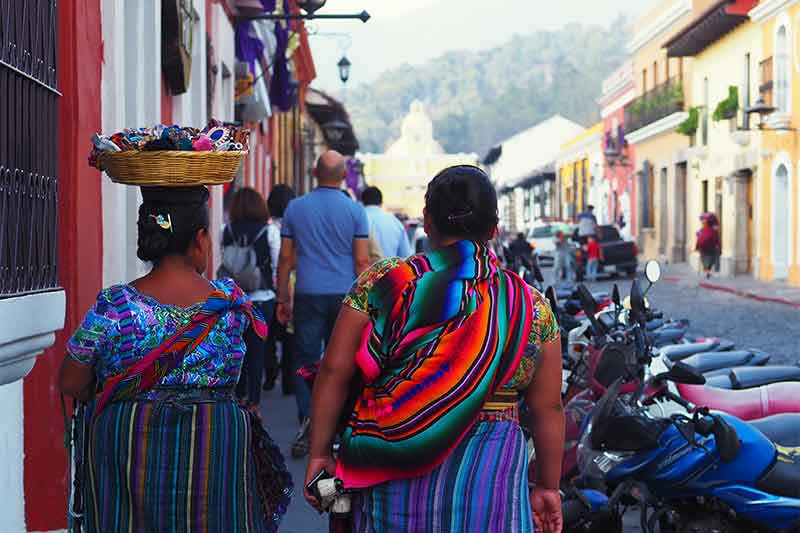 zwei Frauen in typischer guatemaltekischer Kleidung laufen die Straße entlang