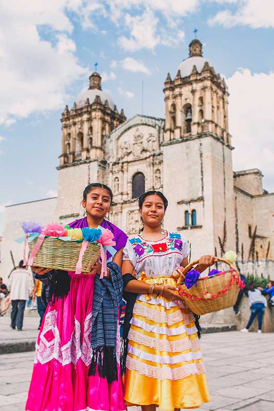 Mädchen in traditioneller Kleidung vor Kirchturm