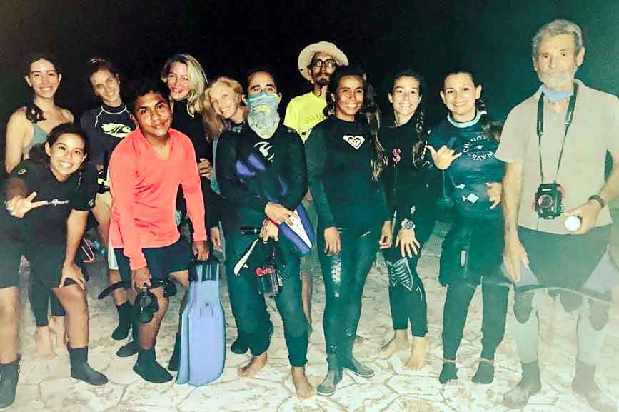Freiwillige in Taucheranzügen am Strand von Cozumel