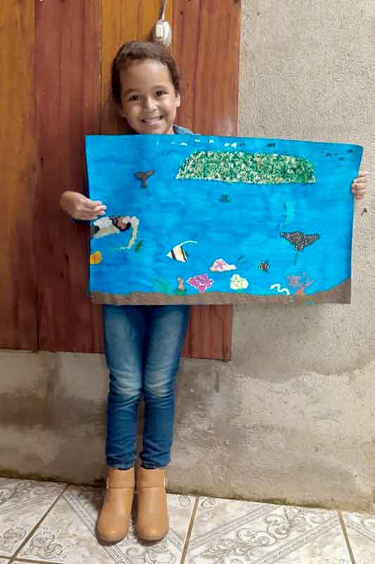 kleines Mädchen hält selbst gemaltes Bild in die Kamera in Costa Rica