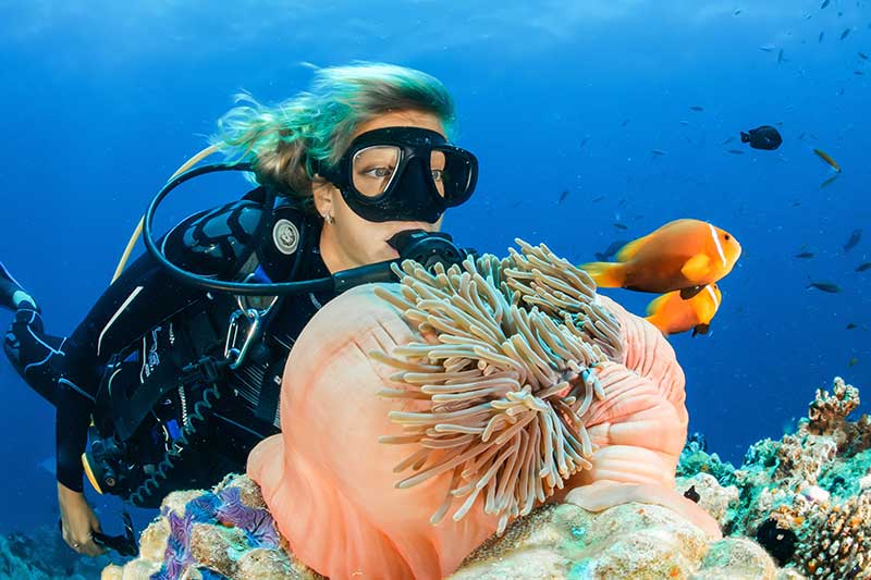 Taucherin auf dem Meeresgrund mit bunten Korallen
