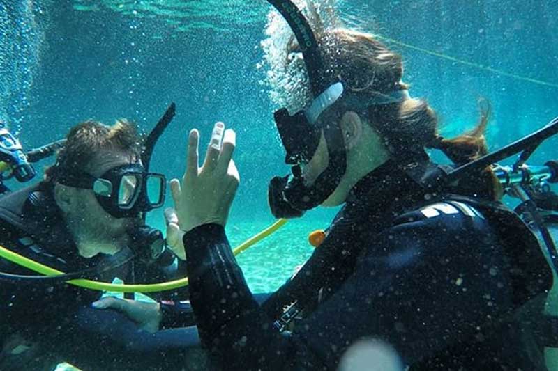 Taucher geben Zeichen unter Wasser in Tulum