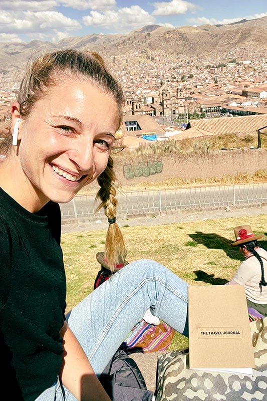 Jenny sitzt vor Aussicht auf Cusco