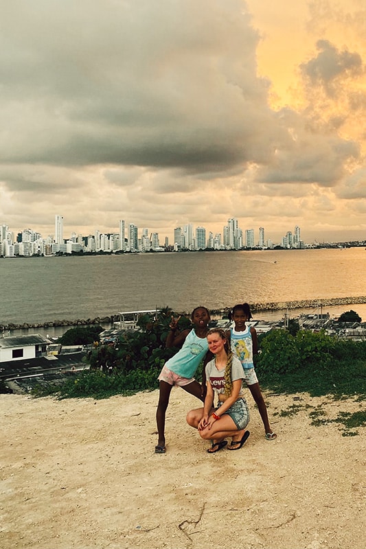 Kathrin malt mit einem Mädchen im Projekt vor der Skyline von Cartagena