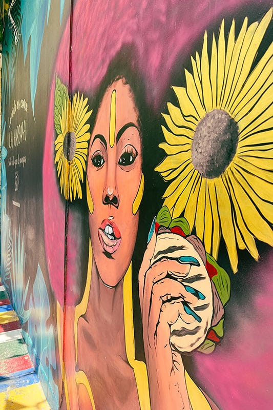 bunte Wandbemalung einer Frau mit großer Sonnenblume