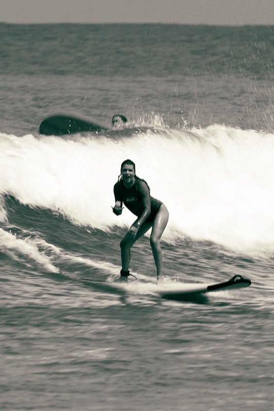 Mädchen auf Surfbrett im Wasser auf einer Welle