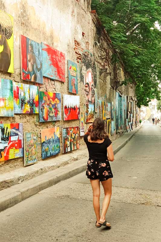 Christina läuft vor einer Mauer mit Gemälden