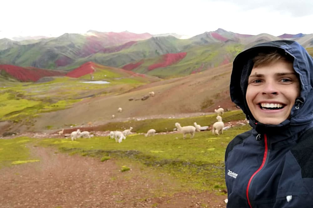 Fabian in Regenjacke vor Wiese mit Lamas