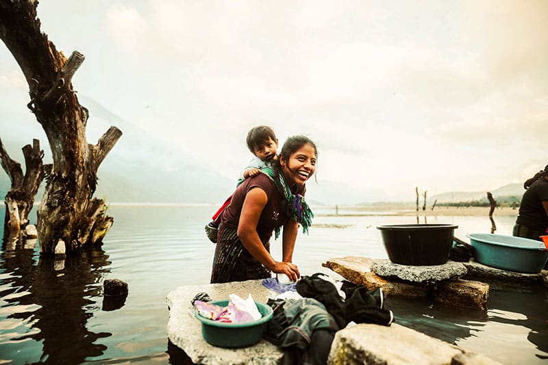Frau lachend mit Kind im See