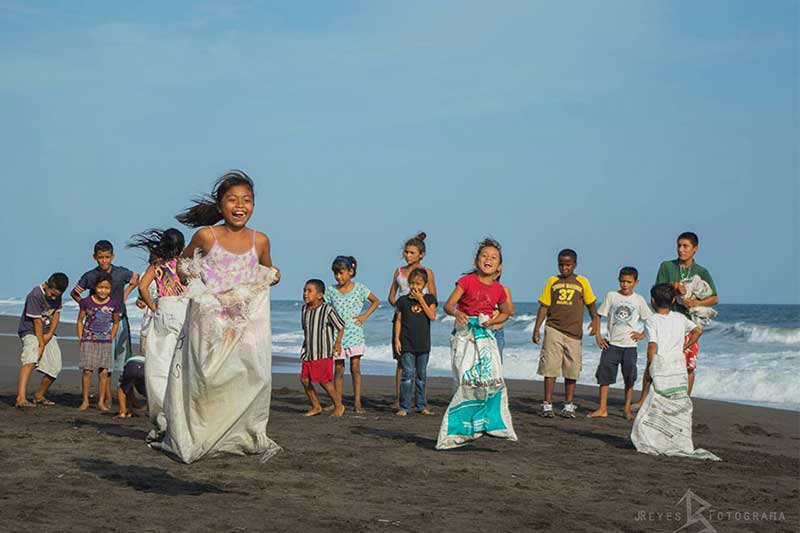 Kinder hüpfen in Säcken am Strand von Guatemala