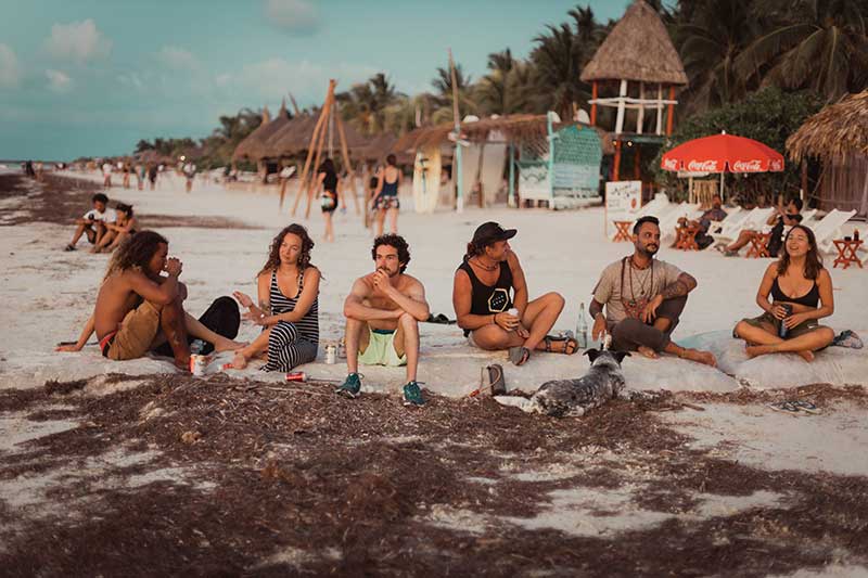 Gruppe Reisender sitzt am Strand und redet in Mexiko