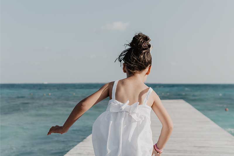 kleines Mädchen läuft auf Steg ins Meer