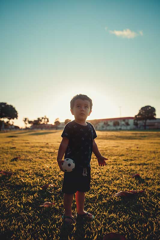 kleines Kind hat Ball in der Hand auf dem Feld