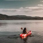 Frau fährt Kayak auf einer Lagune