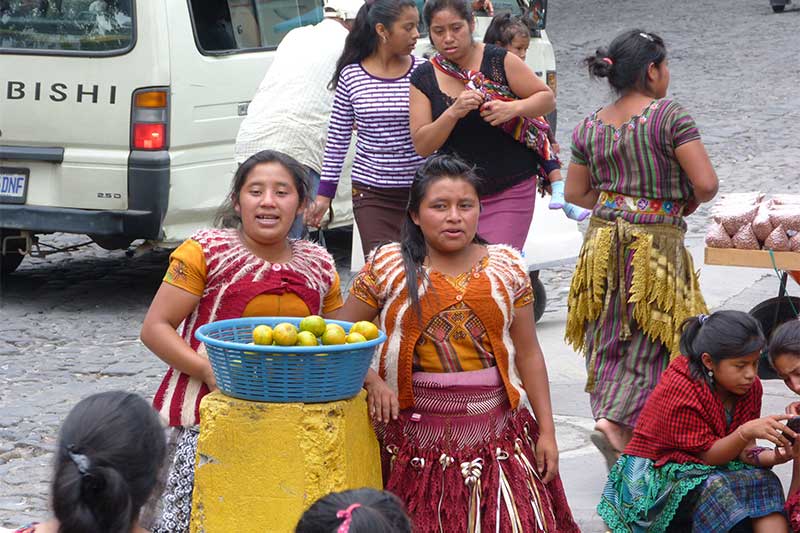 Mädchen in traditionell-guatemaltekischer Kleidung verkaufen Obst