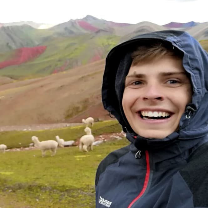 Fabian in Regenjacke vor Wiese mit Lamas
