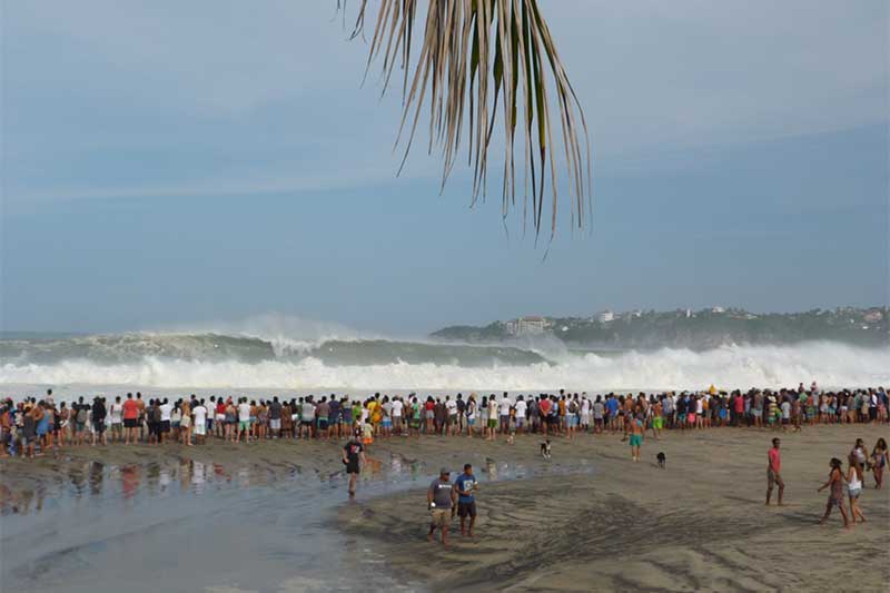 Zuschauer am Strand vor riesiger Welle
