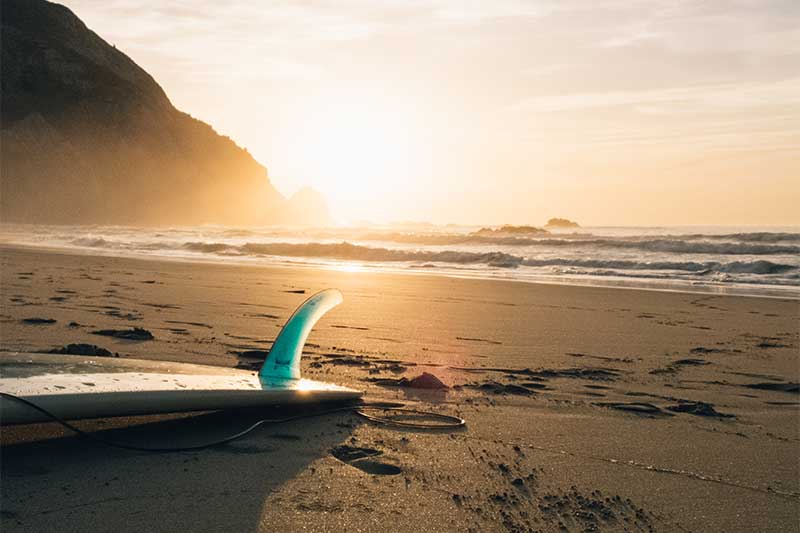 Surfbrett am Strand bei Sonnenuntergang