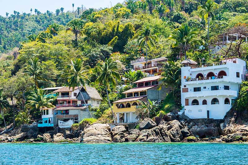 Häuser zwischen Palmen am steilen Ufer gebaut