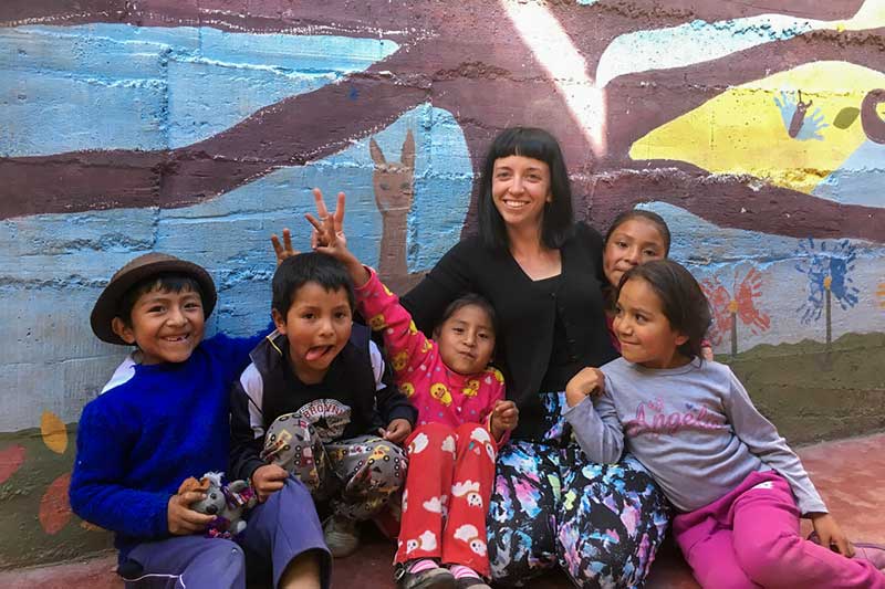 Volunteer laughs with Peruvian children showing Peace