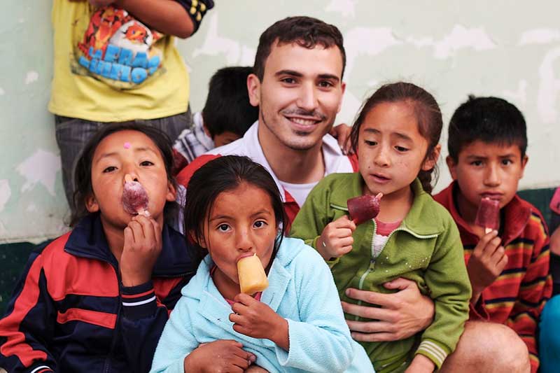 Freiwilliger isst mit peruanischen Kindern Eis