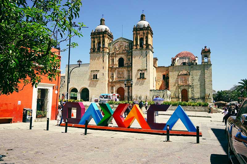 Oaxaca Schriftzug mit Kirche im Hintergrund