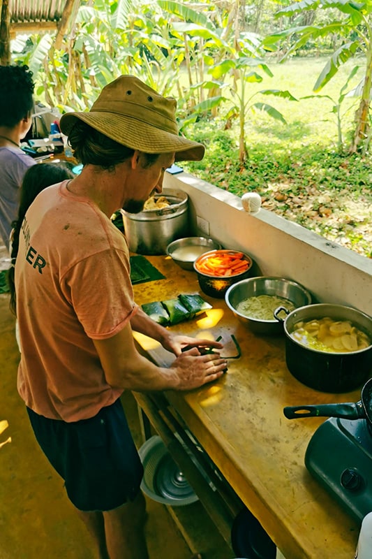 Mann am Kochen in freier Küche mit vielen Töpfen