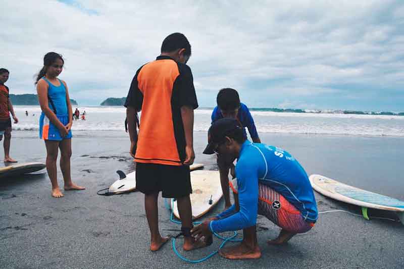 Surflehrer legt Leech an Surfschüler an in Costa Rica