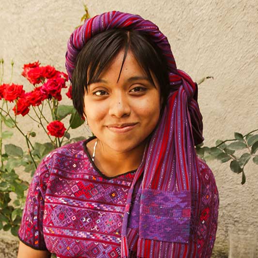 Einheimisches Mädchen mit Tuch auf dem Kopf lächelt in die Kamera im Youth Development Projekt in Antigua in Guatemala