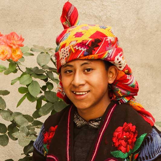 Einheimischer Junge mit Tuch auf dem Kopf lächelt in die Kamera im Youth Development Projekt in Antigua in Guatemala